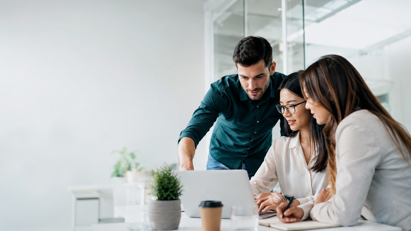 Professional team collaborating around a laptop in a modern office